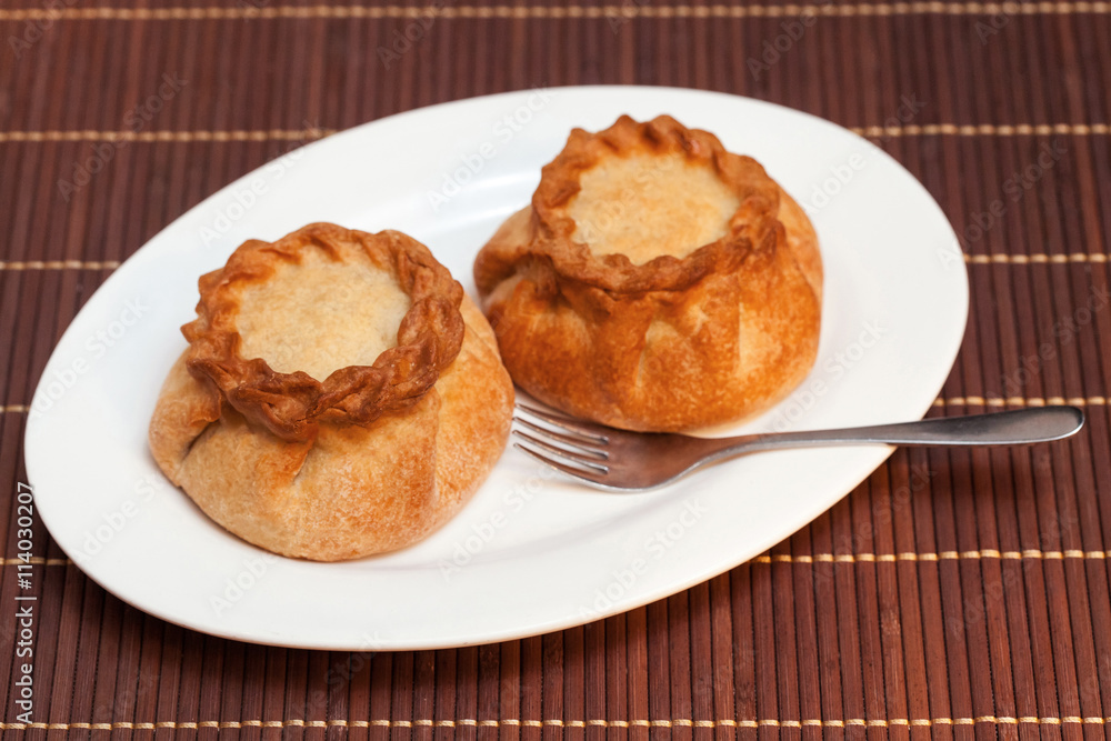 Round pasties stuffed meat on bamboo napkin, close up Round pasties stuffed meat on bamboo napkin, close up