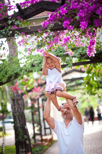 Dad plays and laughs with her baby daughter in blossoming garden