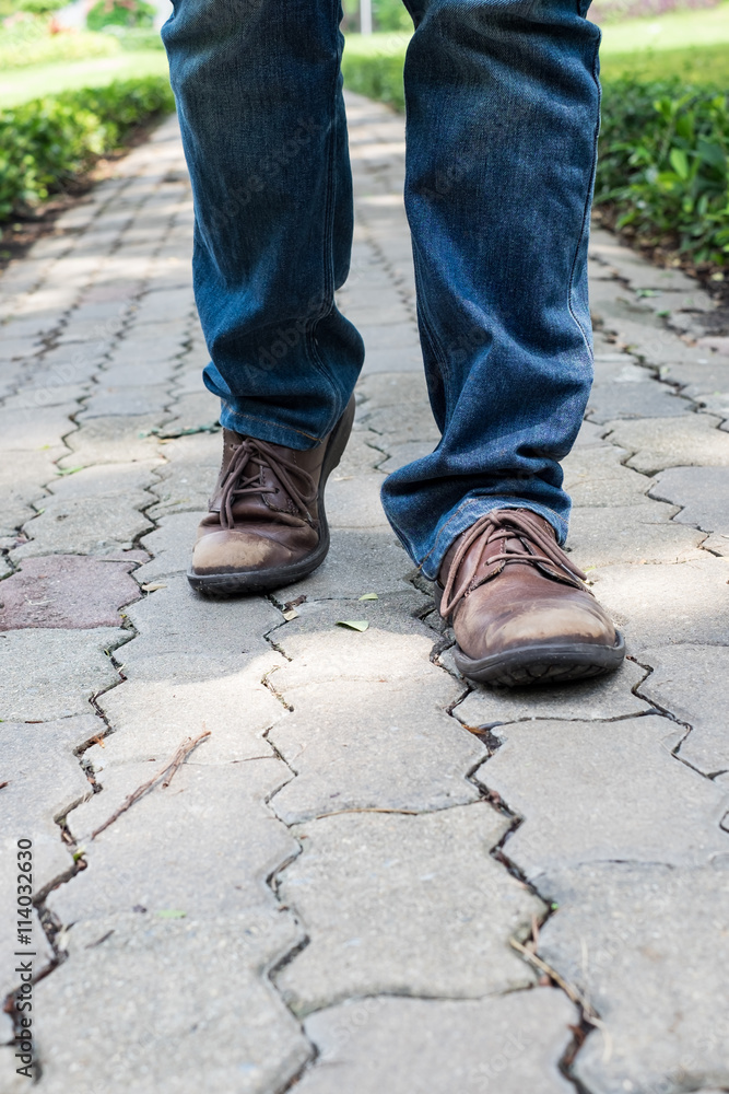 Man wearing jeans walking on the path to the park or garden Man wearing jeans walking on the path to the park or garden