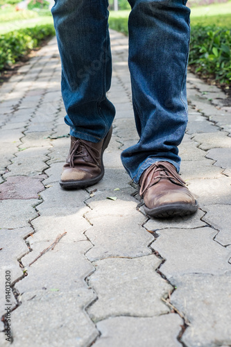 Man wearing jeans walking on the path to the park or garden