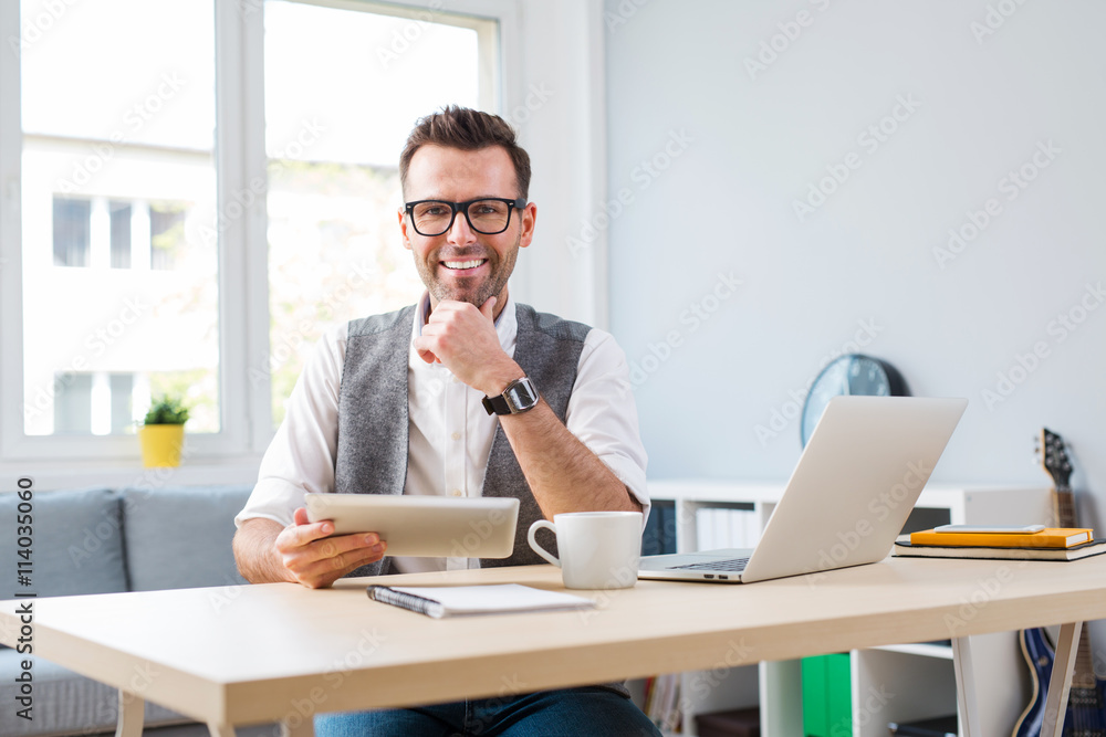 Happy man at home office working on laptop