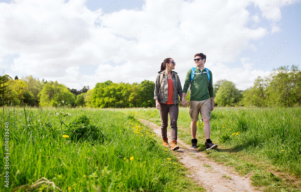 happy couple with backpacks hiking outdoors