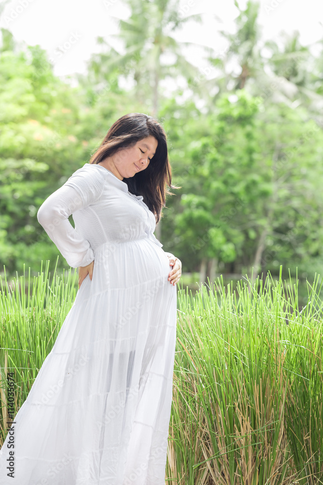 Pregnant woman holding her belly with love on the green field. Pregnant woman holding her belly with love on the green field.