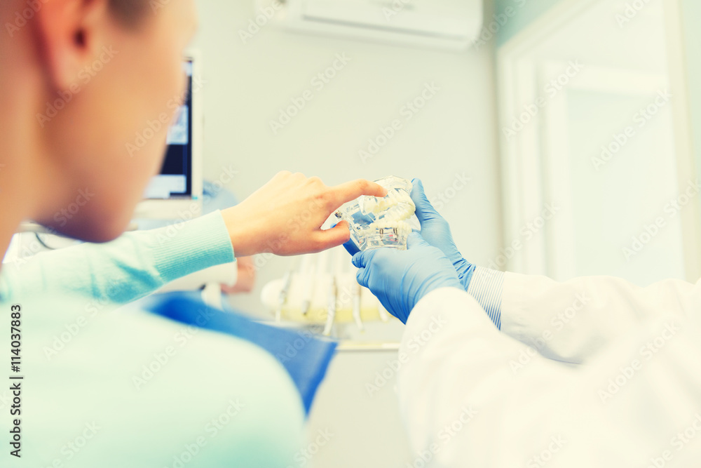close up of dentist with teeth model and patient