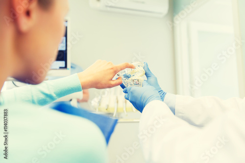 close up of dentist with teeth model and patient