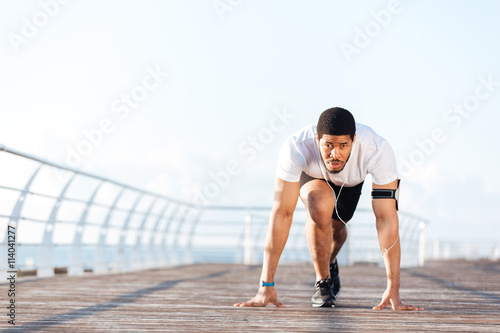 Focused sportsman in running start position on pier