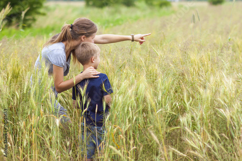 Young woman pointing hand and little boy her son standing in whe photo