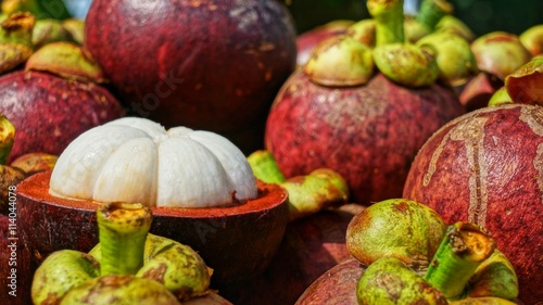 Mangosteens Bunch of fruits, ripe mangosteen fruit halved with pulp visible.