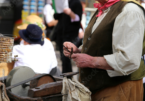 Elder man while sharpens knife in grindstone