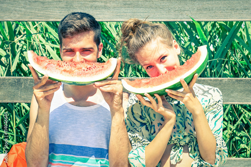 Fotografi Positive couple eating watermelon at countryside picnic - Young friends having