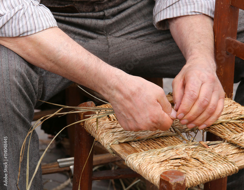 mender of chairs while repairing a chair with straw
