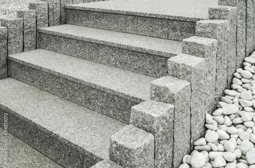 Closeup einer modernen Außentreppe aus Granit mit Stelen und Drainage aus großen weißen Kieselsteinen - Closeup of a modern exterior granite staircase with palisades and drainage of pebbles 