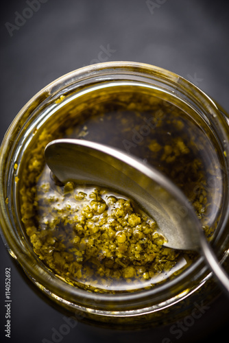 Pesto sauce in the glass jar with spoon vertical