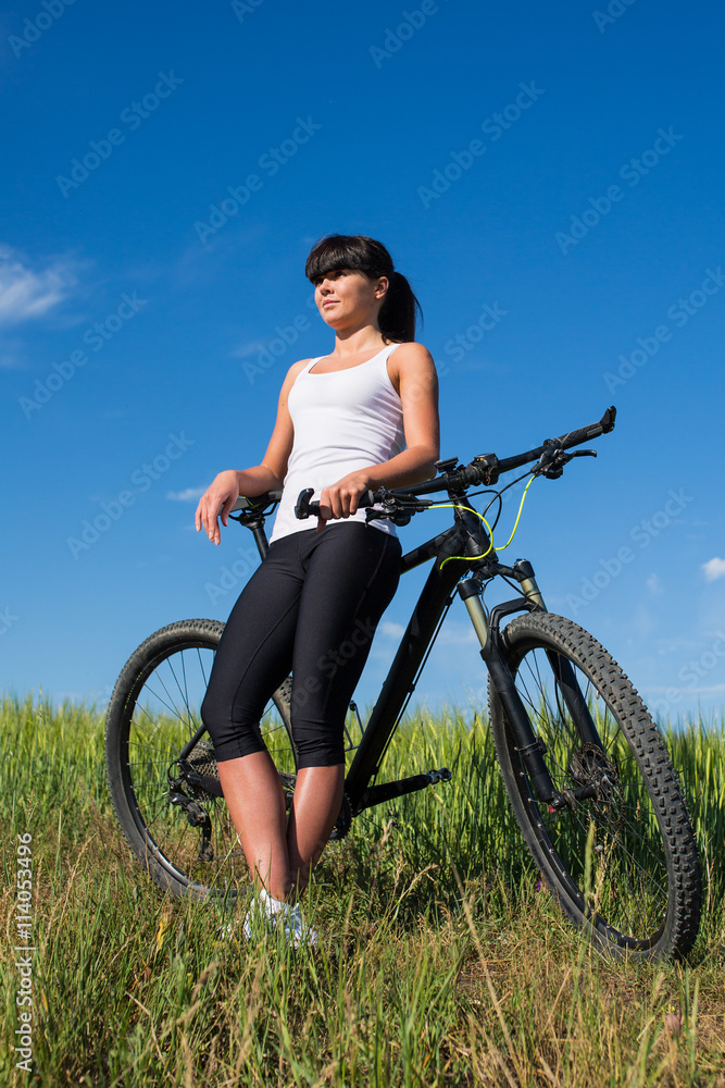 Mountain biking happy sportive girl relax in meadows sunny countryside Mountain biking happy sportive girl relax in meadows sunny countryside