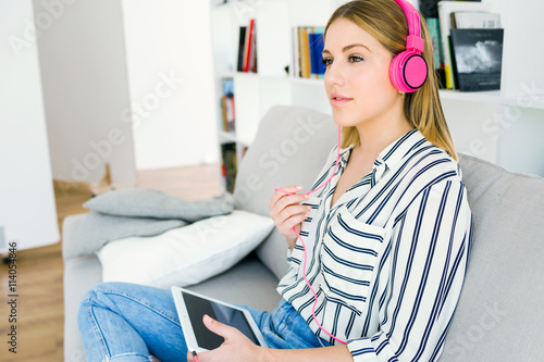 Beautiful young woman listening to music with digital tablet.