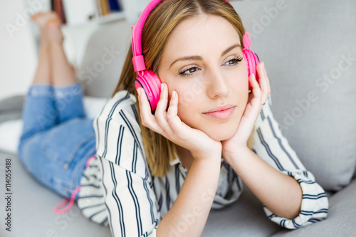 Beautiful young woman listening to music at home.