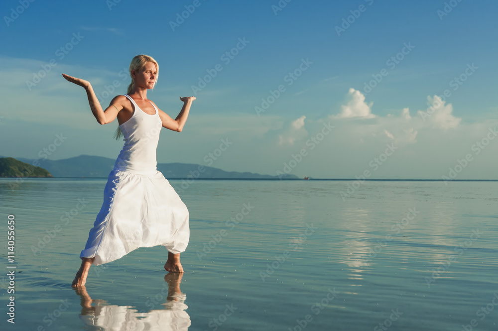 Young woman doing yoga at sunset. Girl doing balance practice at the beach. Young woman doing yoga at sunset. Girl doing balance practice at the beach.