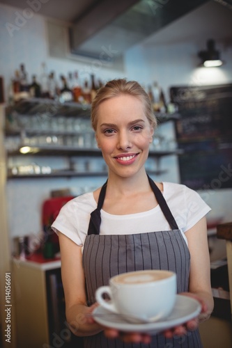 Portrait of confident waitress serving coffee at shop