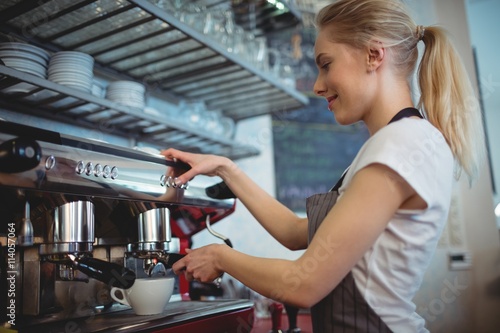 Side view of waitress using coffee maker at cafe photo