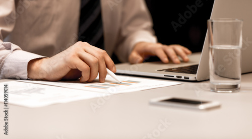 Businessman working on Computer and printed Charts