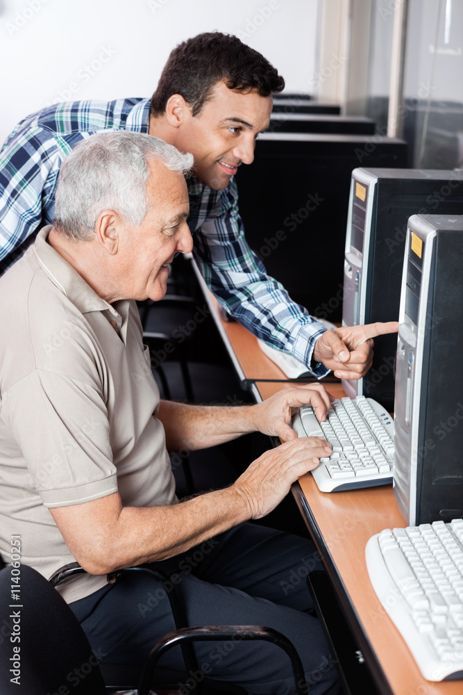 Teacher Assisting Senior Man In Using Computer Teacher Assisting Senior Man In Using Computer