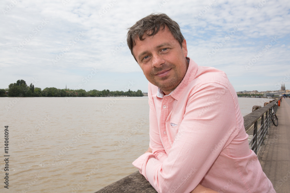 Smiling man in river background with a light pink shirt