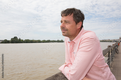 Pensive man in river background with a light pink shirt
