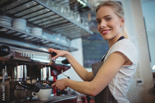 Portrait of waitress using coffee maker at cafeteria