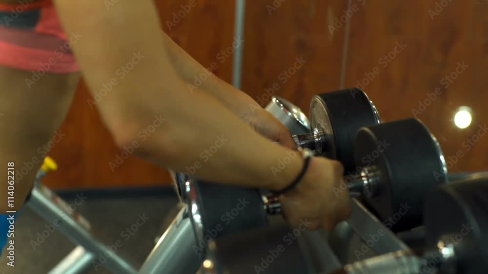 close up female takes dumbbells off stand slow motion close up female takes dumbbells off stand slow motion