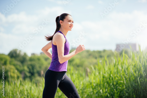 Dreaming, smiling beautiful and attractive woman running in park on sunny day. Sport