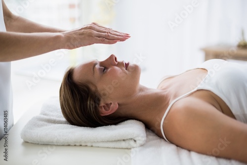 Cropped hands of therapist performing reiki on woman photo