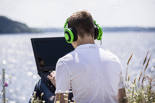 teenager working at the computer on the river bank