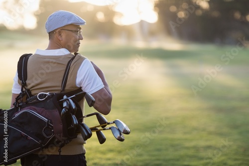 Rear view of mature man carrying golf bag 