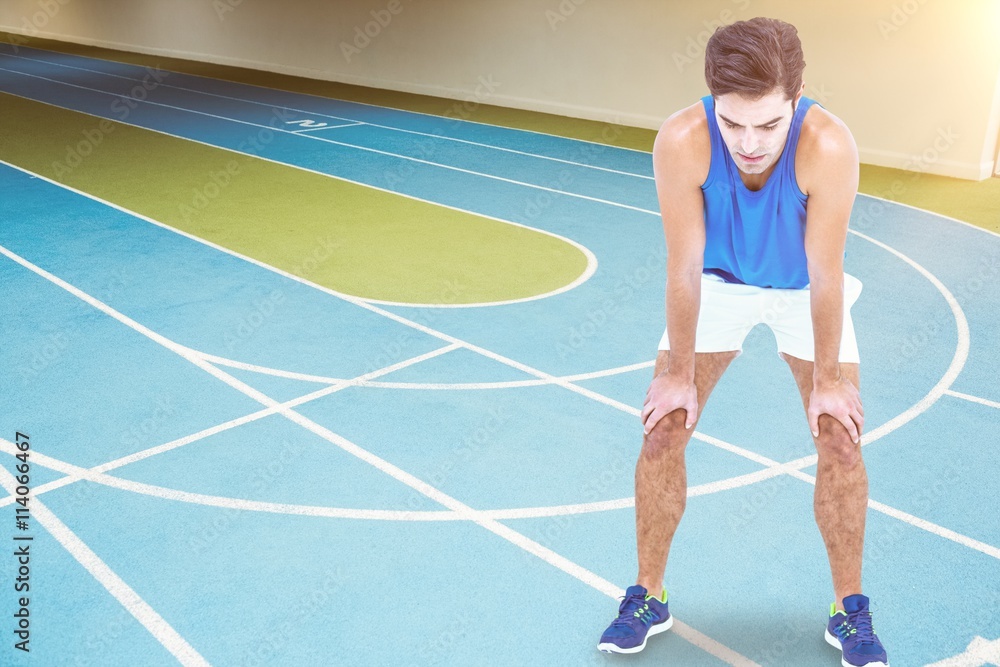 Tired athlete standing with hand on knee Tired athlete standing with hand on knee