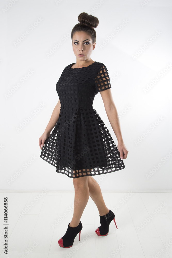 Fashion Model With Hair Bun Wearing Black Dress And Black Red Fancy High  Heels Shoes Posing At Studio Over White Background Stock Photo | Adobe Stock