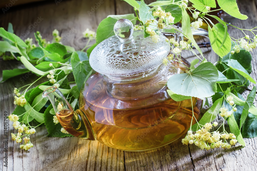 Useful linden tea in glass teapot, branches linden flowers and l Useful linden tea in glass teapot, branches linden flowers and l