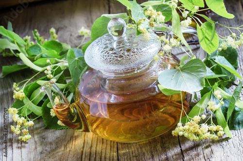 Useful linden tea in glass teapot, branches linden flowers and l