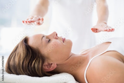 Midsection of therapist performing reiki treatment on woman