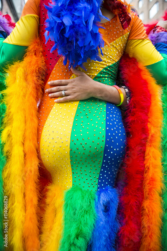 Shapely drag queen in dramatic costume with all the colors of the rainbow poses with admirers during the annual gay pride parade in New York City