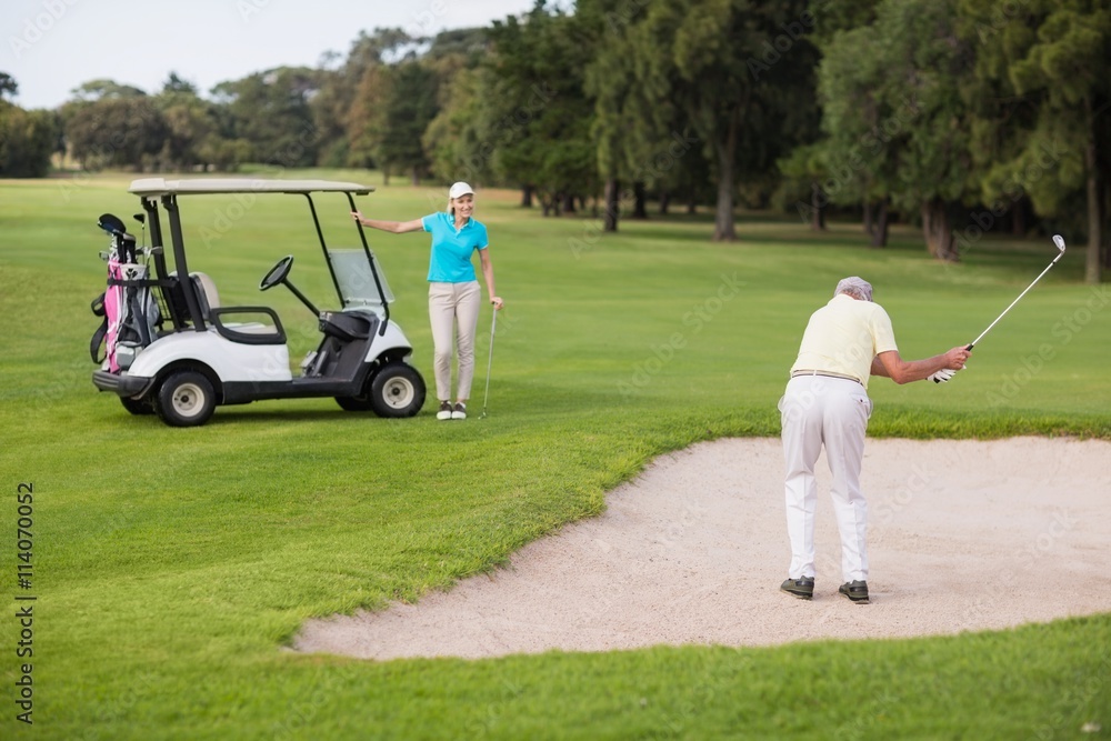 Obraz premium Mature golfer standing on sand trap by woman 