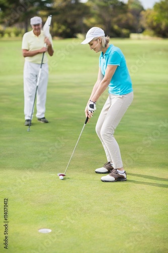 Woman playing golf while standing by man