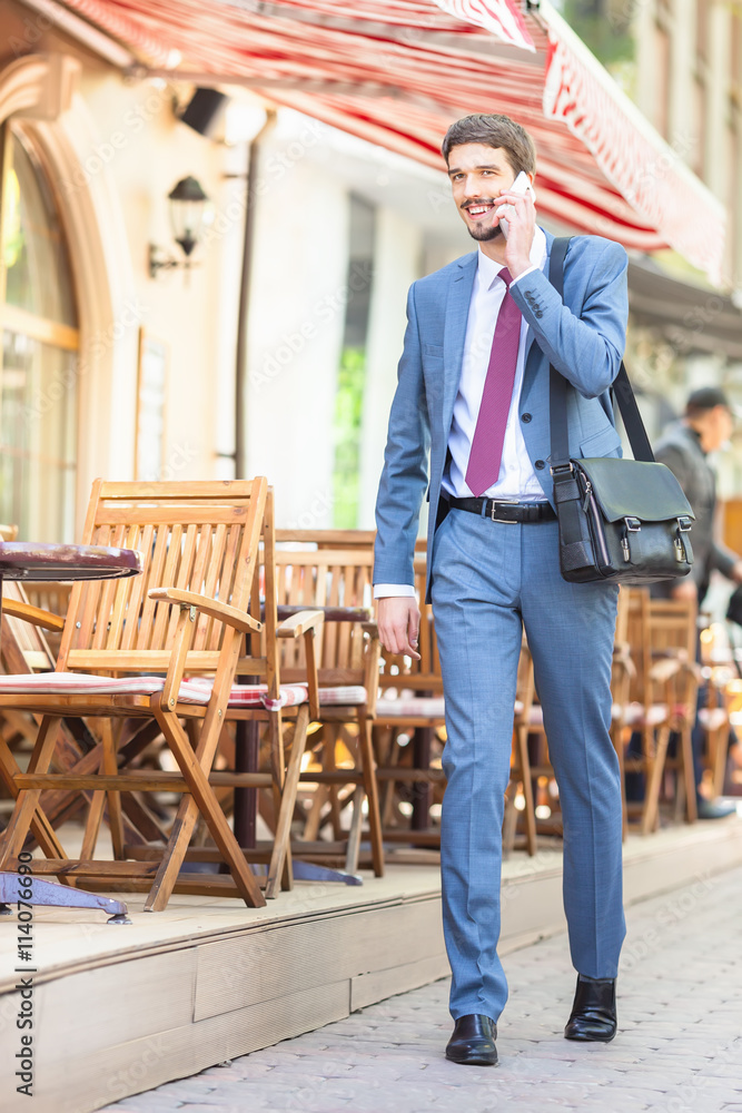 Fototapeta premium Successful businessman talking by mobile phone and walking