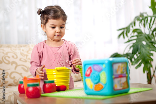 Cute little toddler girl playing with toy in room