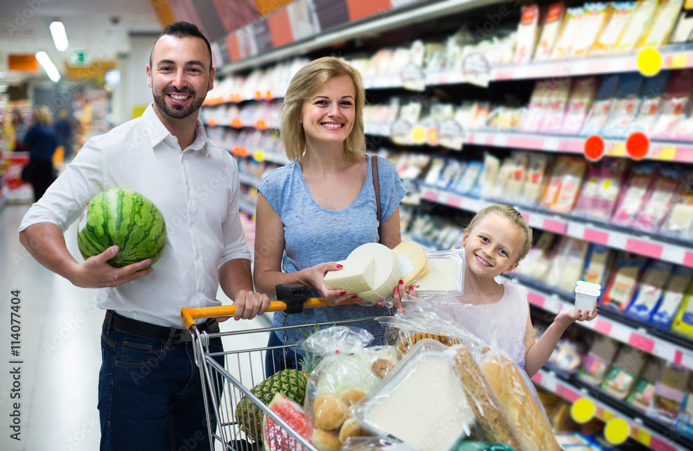 Portrait of  family standing with full cart in supermarket