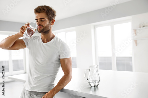 Handsome Man Drinking Glass Of Fresh Water Indoors In Morning