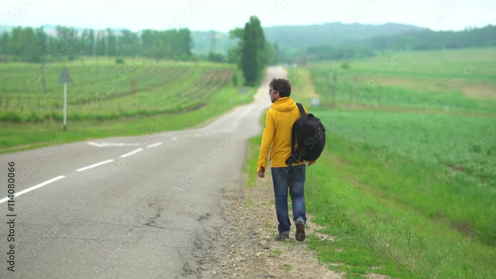man hitchhiking in the countryside, he walk on an empty road without cars man hitchhiking in the countryside, he walk on an empty road without cars