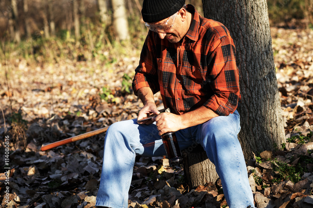 Senior lumberjack in forest. He is resting and drinking beer. Senior lumberjack in forest. He is resting and drinking beer.
