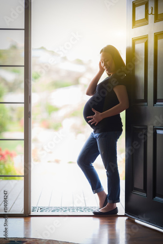 Happy Chinese Pregnant Woman Standing Silhouetted in Doorway.