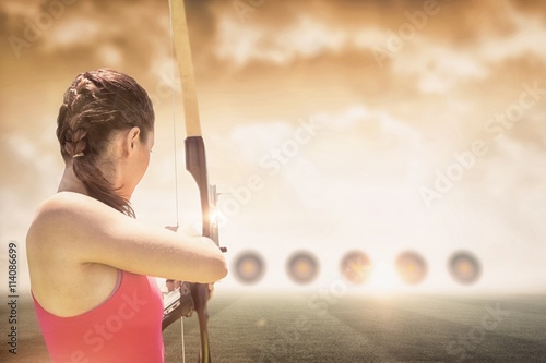 Fototapete Rear view of sportswoman doing archery