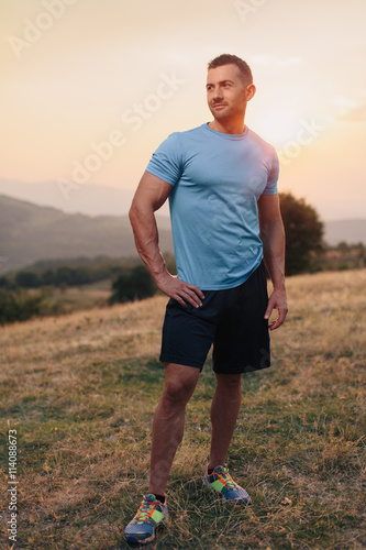 Athletic man in his 30s resting with his hands on his hips while jogging outdoor